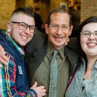 Three guests hugging and smiling at Scholarship Dinner 2019